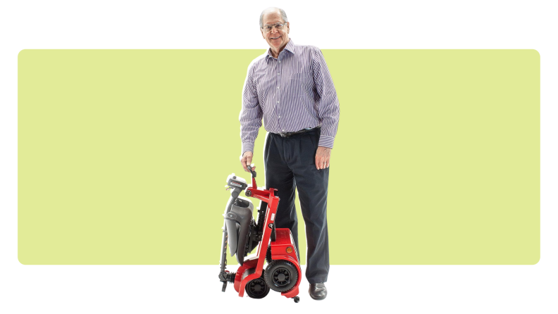 The Shoprider mobility scooter being folded and carried by a man
