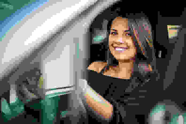 A smiling woman behind the steering wheel of a car.