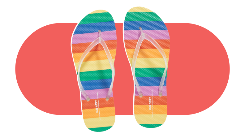 A pair of rainbow striped flip flops on a coral background.