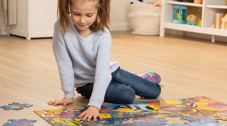 A child sits on the floor and does a puzzle