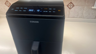 The Coosri Dual Blaze Smart air fryer on countertop in front of tiled wall.