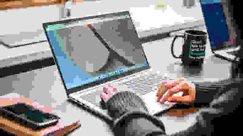 The Galaxy Book being used on a desk, with a cup of coffee and a cell phone next to it.