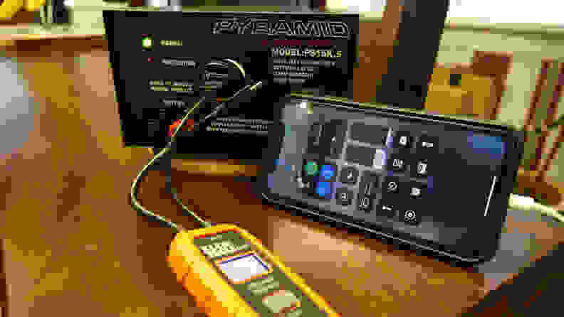 A bench power supply and multimeter are plugged into an iphone to measure voltage.