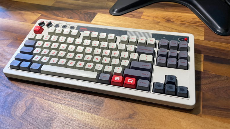 The 8Bitdo Retro Mechanical Keyboard and mouse pad sitting on a wood table.