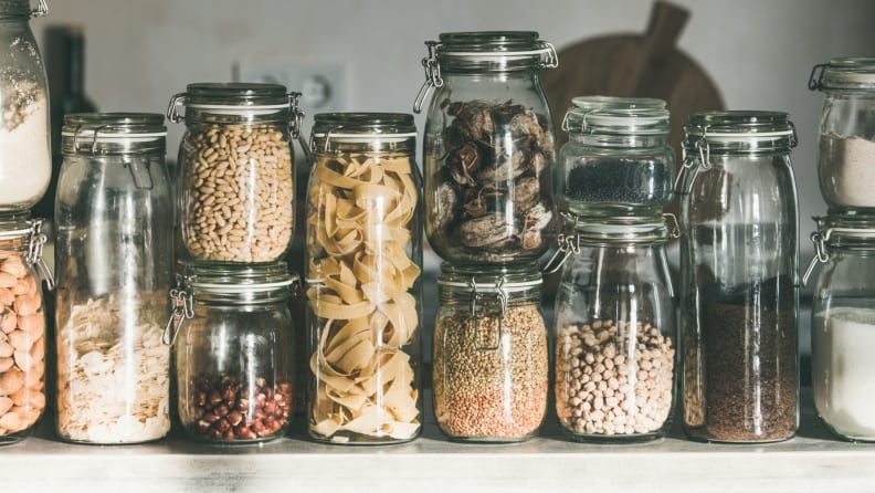 A cabinet full of mason jars house spices, pasta, and nuts.