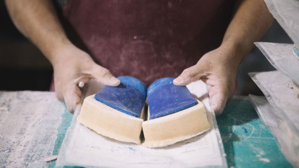 Hands hold blue insoles attached to thick molds