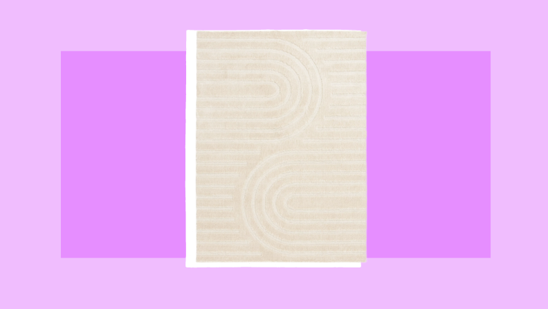 Cream colored rectangle area rug to place in a dorm room.