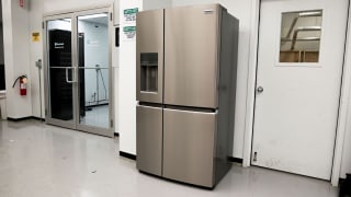 Stainless steel refrigerator with top top and two bottom doors sits inside of testing lab