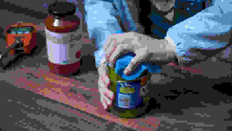 An pair of hands trying to open a jar of pickles
