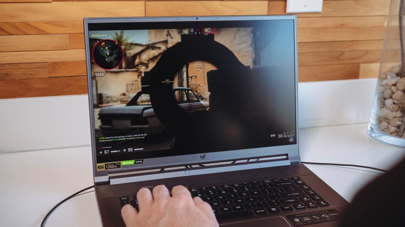 A person games on the laptop with a plug-in mouse.