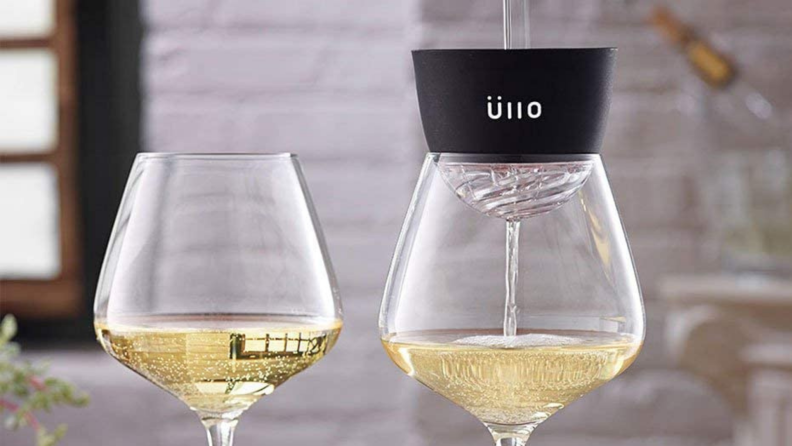 Two wine glasses filled with white one. Glass on the right is topped with the Üllo wine purifier.