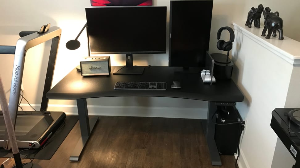 A computer desk with two monitors, a radio, and keyboard.