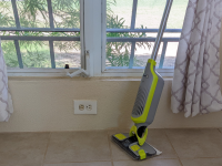 The Shark VacMop leaning against a sunny window with white curtains