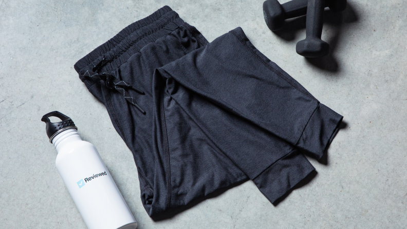 Close up of dark joggers next to a water bottle and weights.
