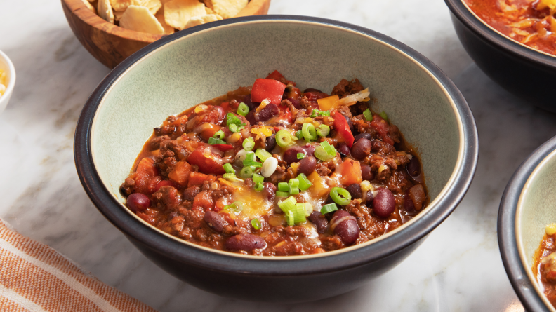 Bowl of chili topped with cheese and scallions