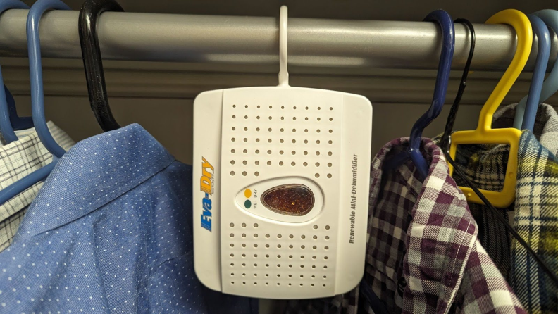 The Eva-Dry 333 mini dehumidifier hanging from a clothes rail in a closet using desiccant to reduce humidity.