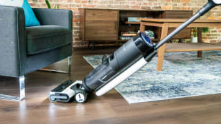 The Tineco S7 Pro cleans the floor between a rug and chair.