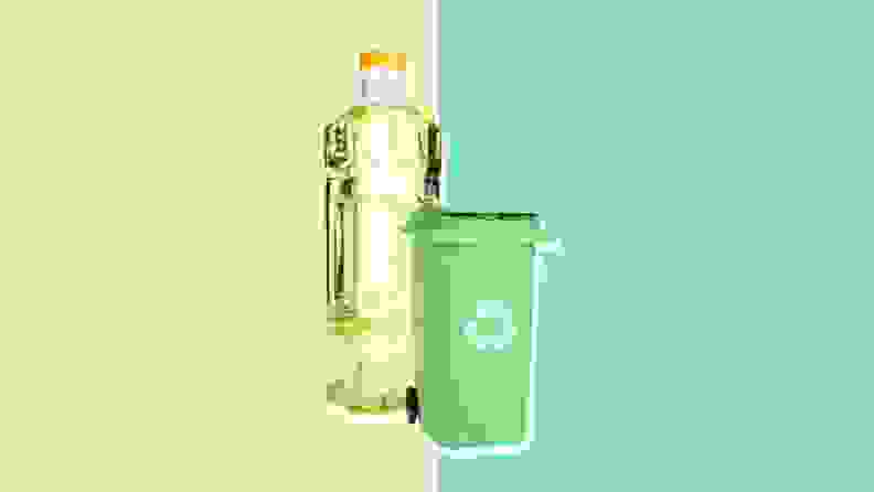 Bottle of oil and recycling bin on green background