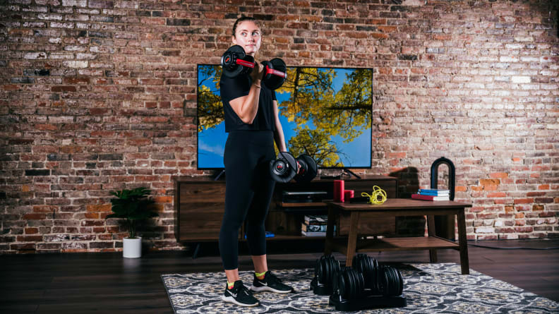 A woman using the Bowflex SelectTech 552 adjustable dumbbells.