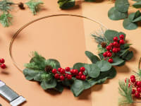 A hoop wreath sitting at the center surrounded by fake flowers and floral wire.