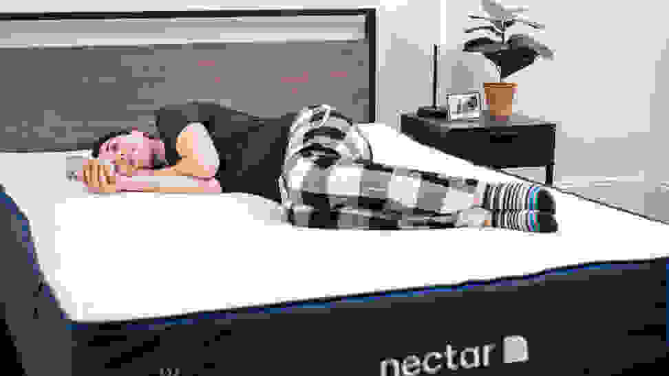 A woman reads her phone on the Nectar mattress