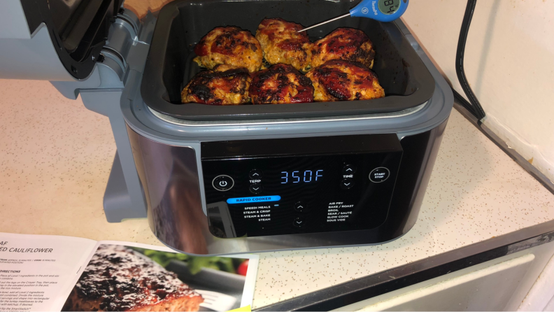 The air fryer with cooked chicken wings inside.