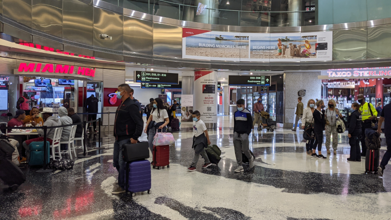 A crowd of people walk though an airport terminal in 2021.