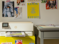 An HP Envy Inspire printer on a colorful desk setup, included with the HP All-In Plan subscription.