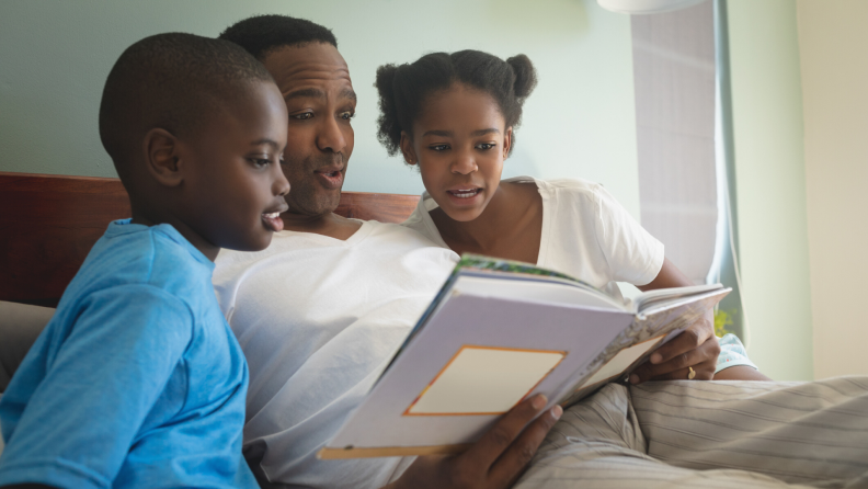 Father reading a bedtime story to his son and daughter