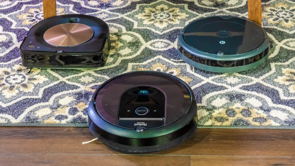 A group of three iRobot Roomba models on the capret