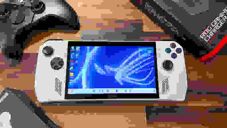 A white handheld console surrounded by controllers and boxes