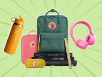 On a light green background: An orange HydroFlask water bottle, one pink and one green Fjallraven backpack, a pair of pink headphones, and a stack of notebooks.
