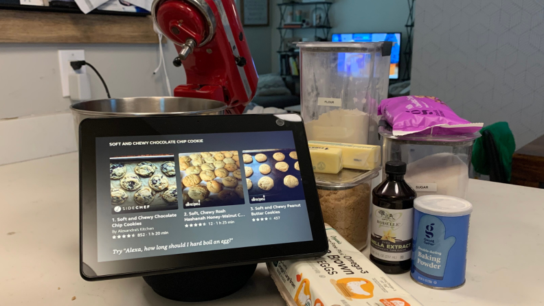 The Amazon Echo Show 10 setup next to a stand mixer and ingredients for chocolate chip cookies on a kitchen counter
