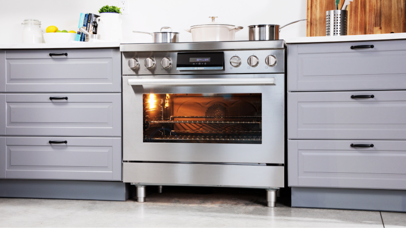 The Bosch HIS8655U 36-in Induction Range shot from afar with the oven light on, surrounded by cabinetry