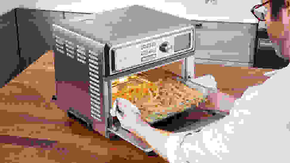 A man pulls a try full of french fries from the Cuisinart Digital Air Fryer Toaster Oven.
