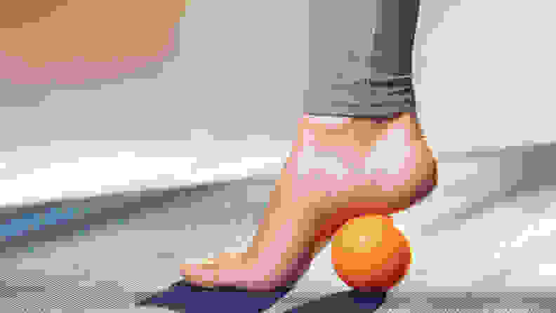 Myofascial release of hyper-movable muscles of the foot with a massage ball on a gymnastic mat at home. Prevention of leg fatigue after wearing high heel shoes.