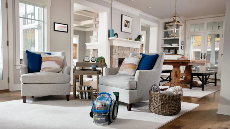 Small Bissell carpet cleaner sitting on floor in modern living room.