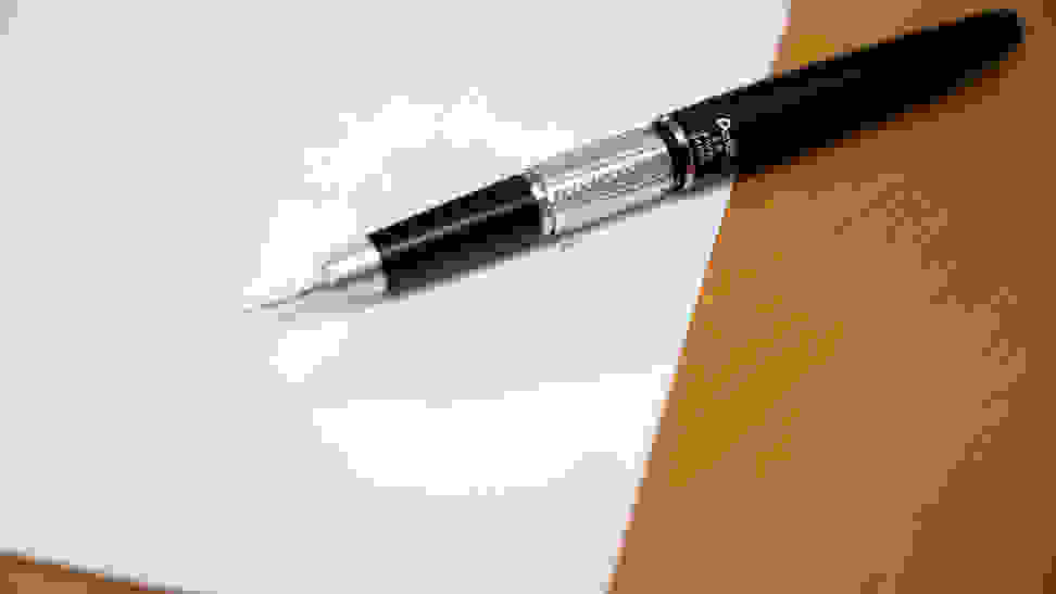 Close-up of a silver and black mechanical pencil on a desktop, along with a handwritten page of notes.