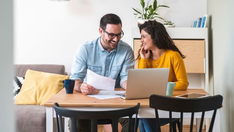 A man and woman look over documents as they sit at kitchen table