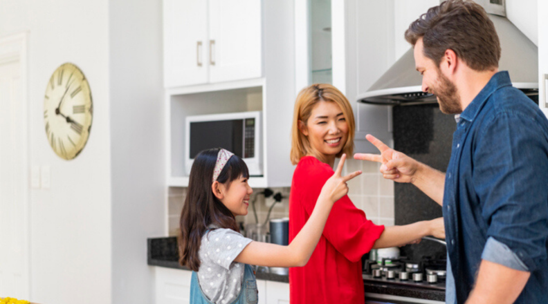 A family plays rock, paper, scissors in the kitchen