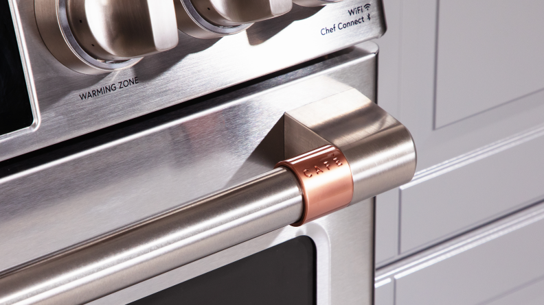 Close-up of a customizable handle detail of the Café CHS900P2MS1 range set in copper.