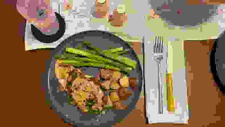 An overhead photo of salmon, roasted potatoes, and steamed asparagus on a dark grey plate.