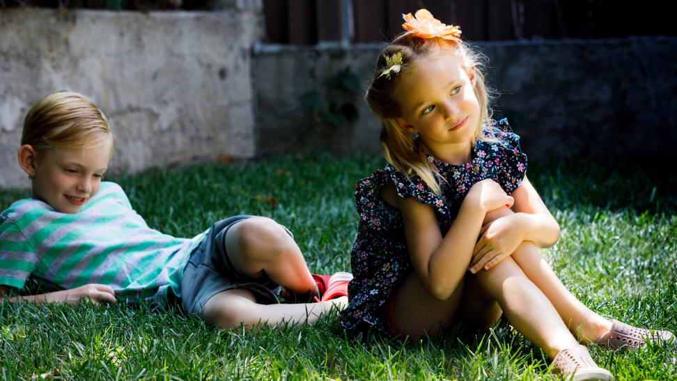 Two children sit on the grass.