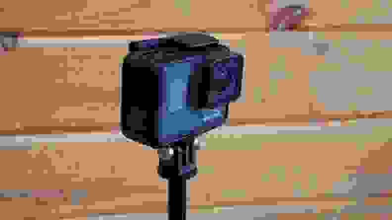 Close up of a GoPro camera against a paneled wall.