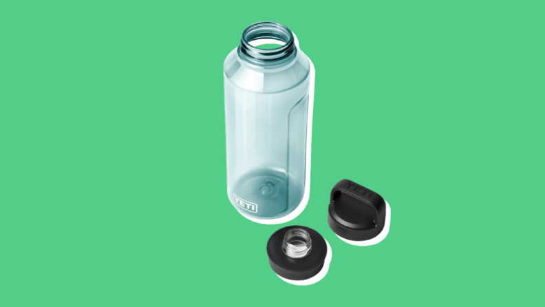 The new Yeti Yonder water bottle with its two caps sitting next to it, on a green background.