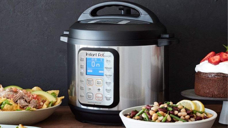 An image of an Instant Pot Smart Wi-Fi on a countertop surrounded by dishes of food.