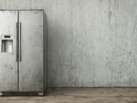 A free-standing refrigerator posed against a blank wall