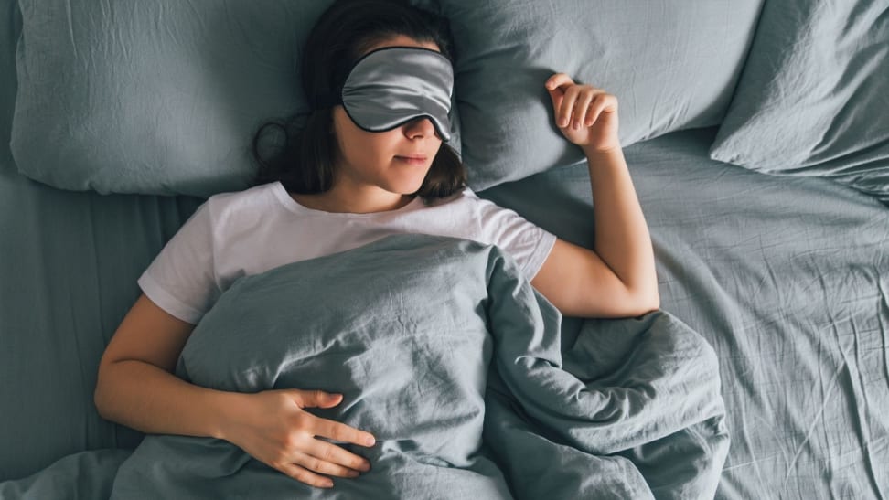 Person lying in bed on their back with a sleep mask on
