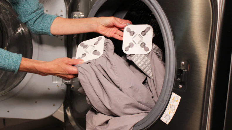 person adding grey sheets to washer