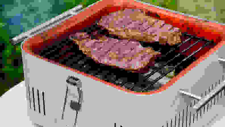 On the Everdure Cube charcoal grill in grill, there are two steaks.